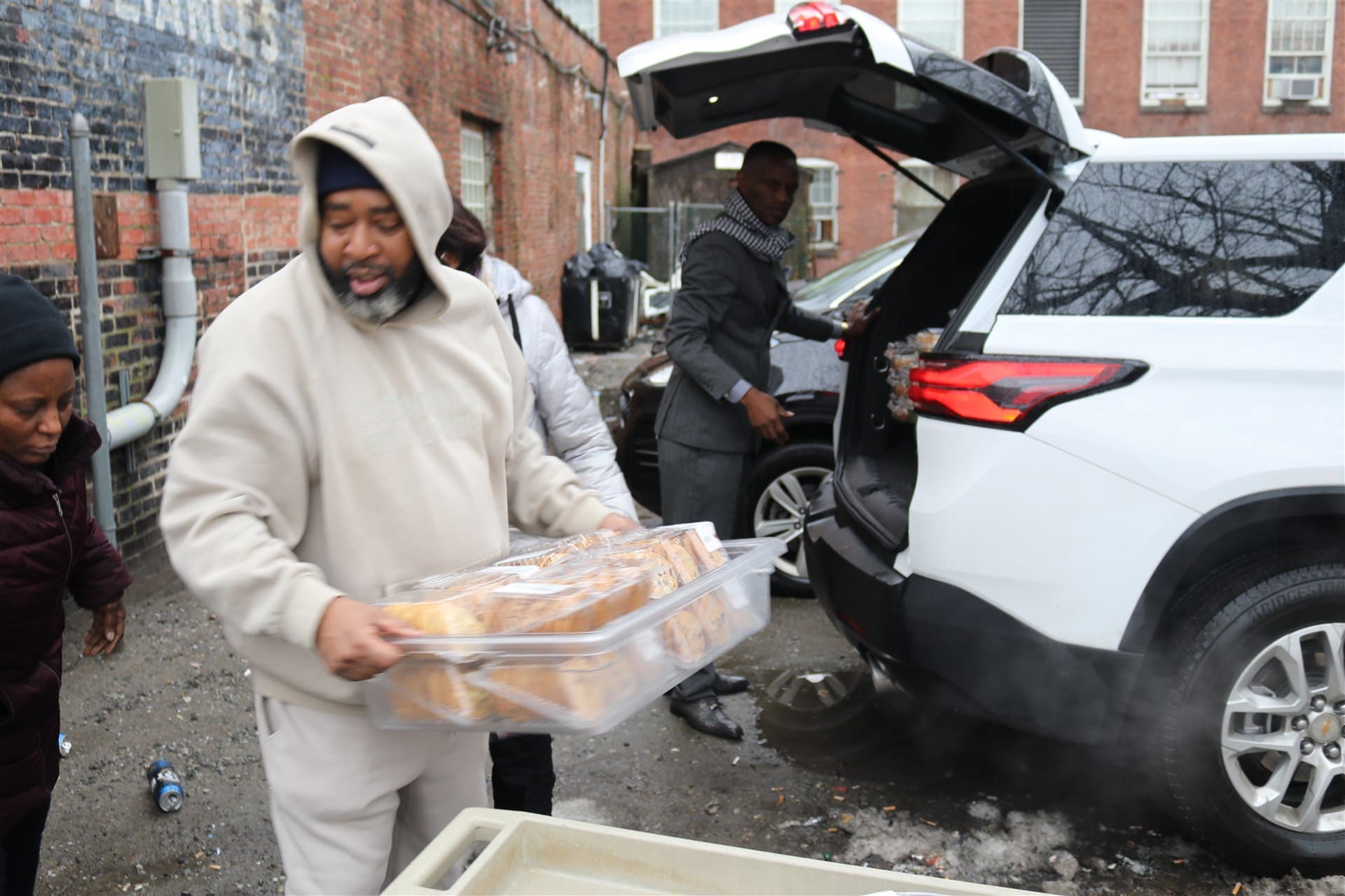 An HESM volunteer carrying trays of prepared food from a vehicle during Boston outreach