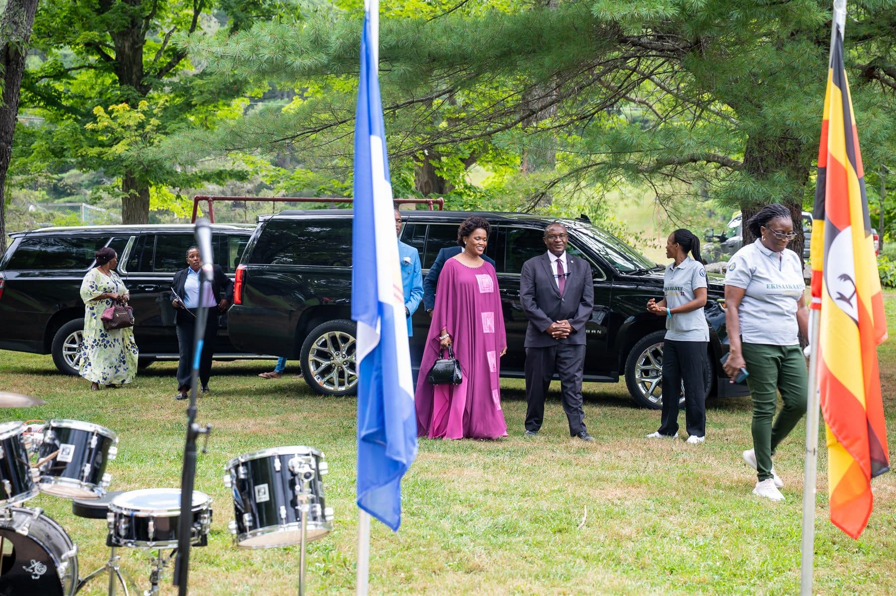 The arrival party standing at attention beside the Buganda and Uganda flags as the royal convoy pulls in