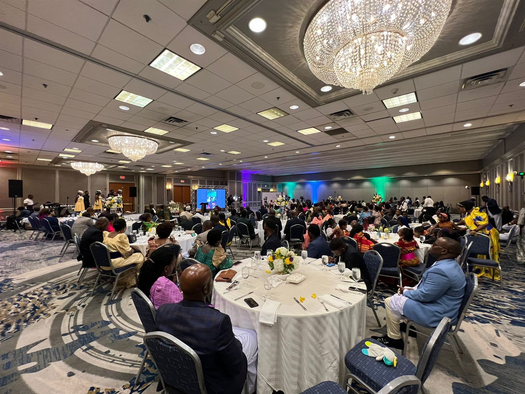 Families, campers and guests seated around dinner tables at the Ekisaakaate Boston closing ceremony