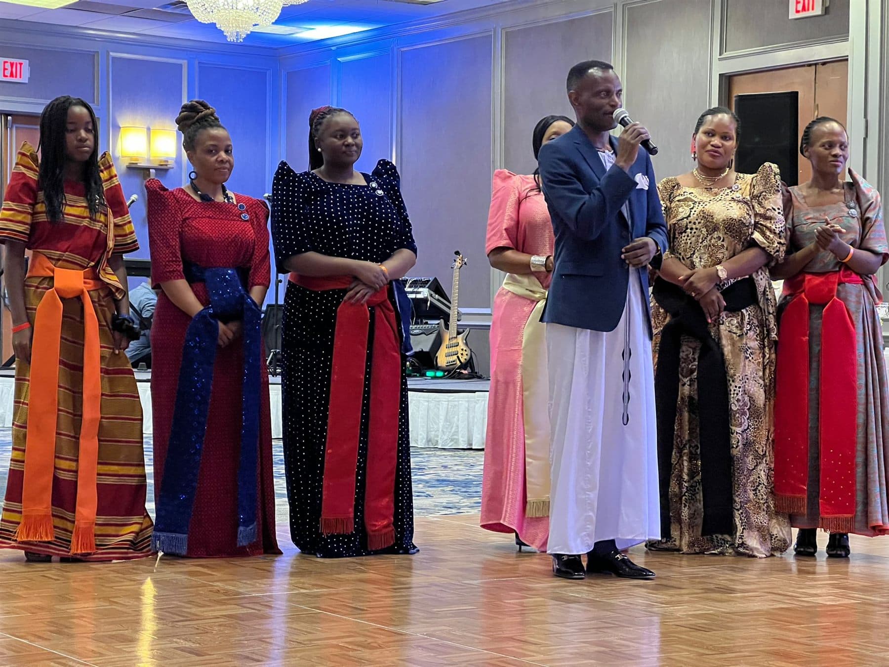 Prince Henry Edward Ssuuna speaking on stage with Ekisaakaate Boston organisers beside him