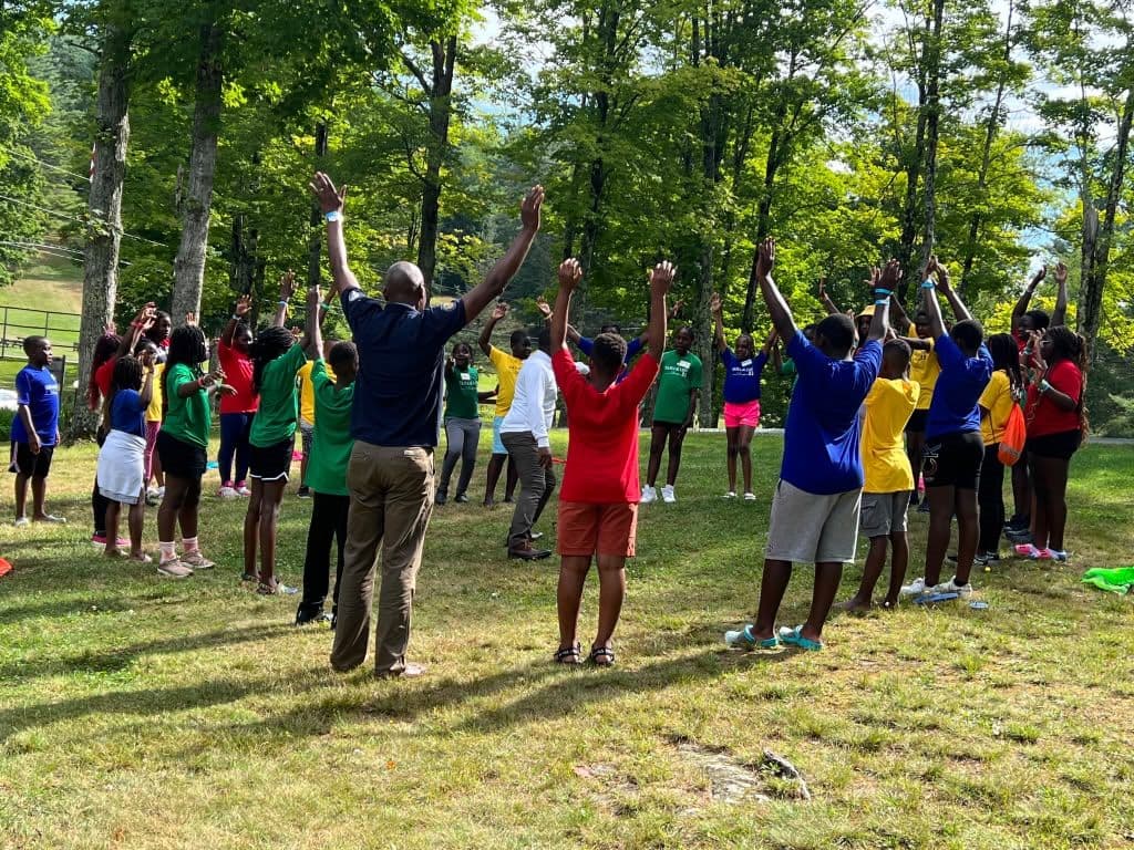 Campers in their team colours raising their arms together in a cheer