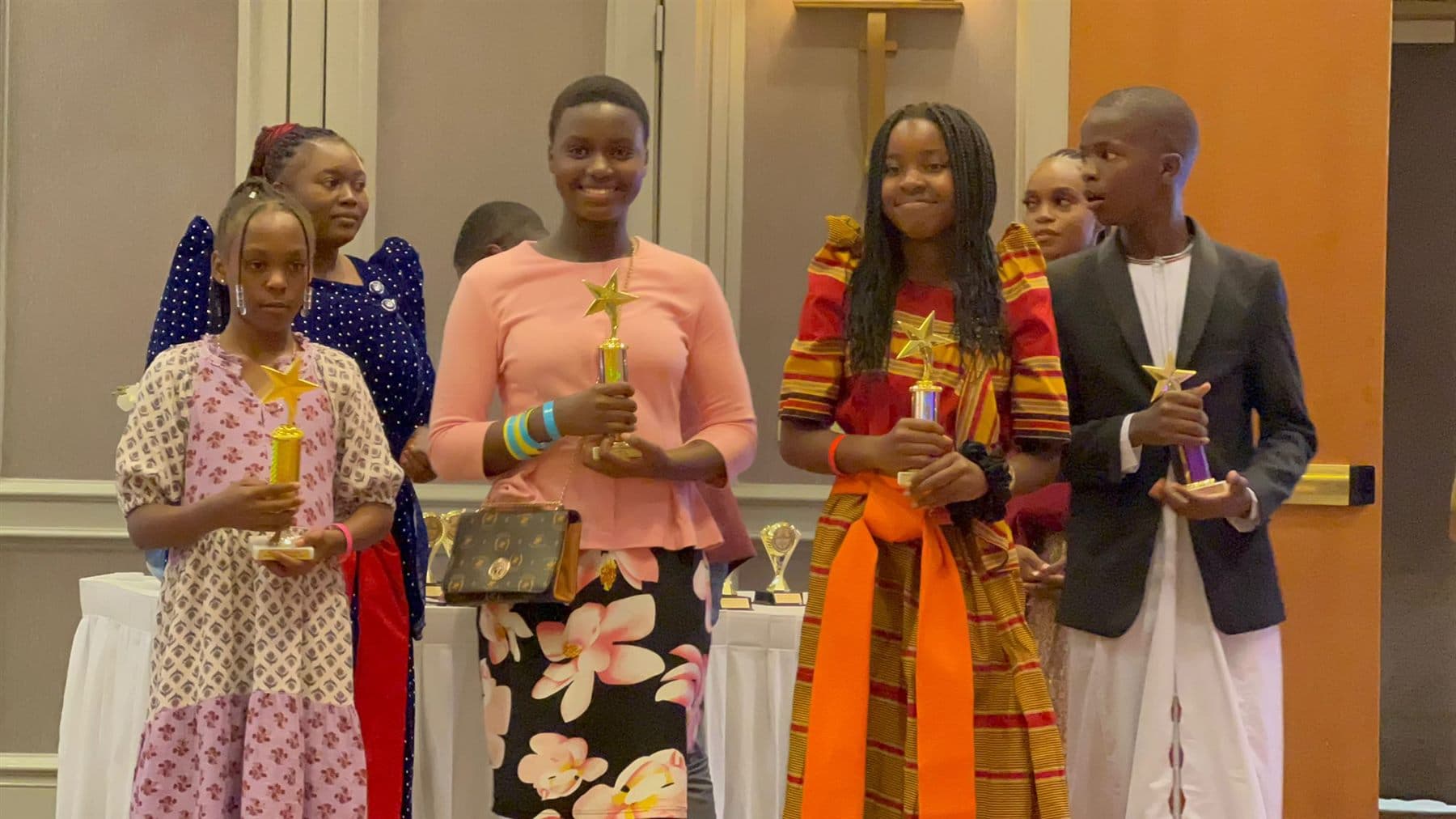 Four young Ekisaakaate Boston participants holding star trophies during the closing ceremony