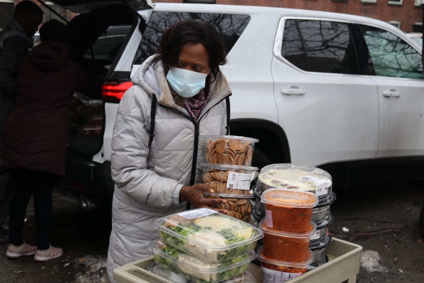 A volunteer arranging prepared meals on a cart beside the outreach vehicle