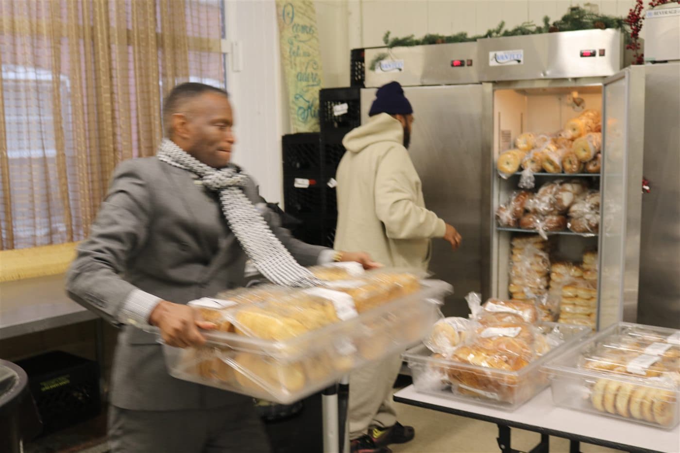 A volunteer carrying containers of baked goods across the preparation room