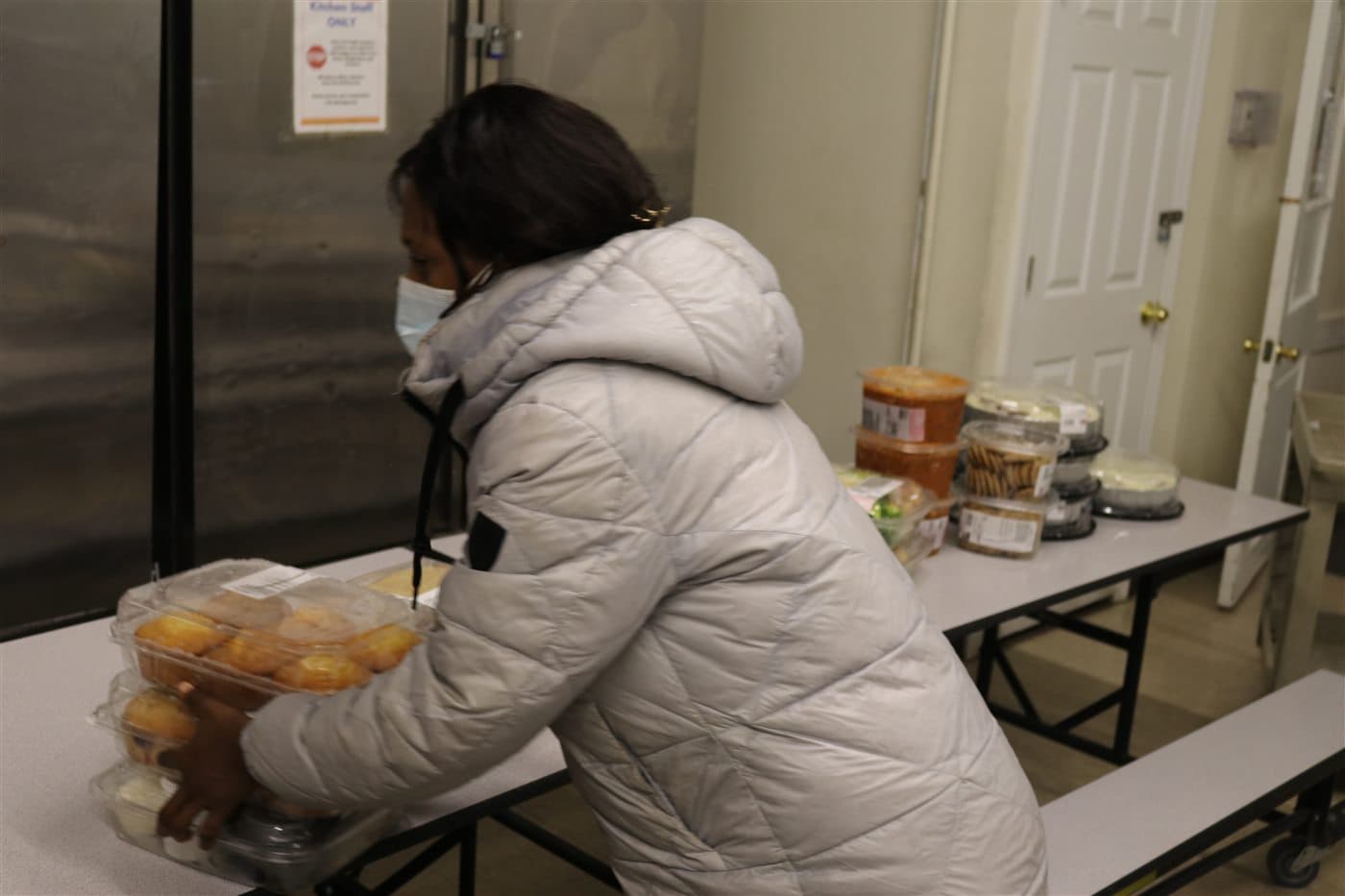 A volunteer placing prepared food containers on a table