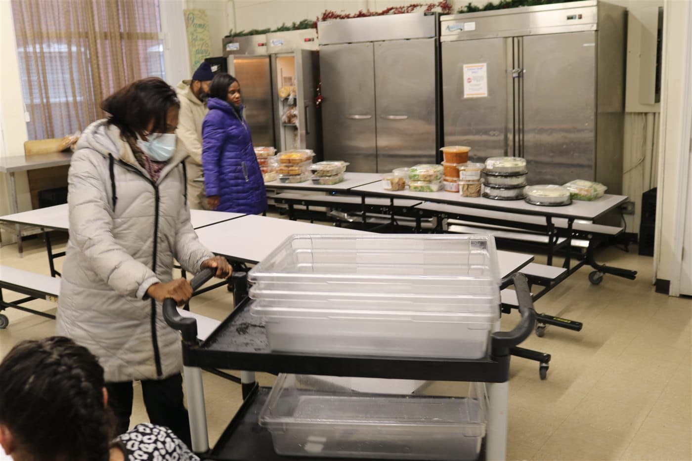 A volunteer standing beside carts and storage bins in the preparation room