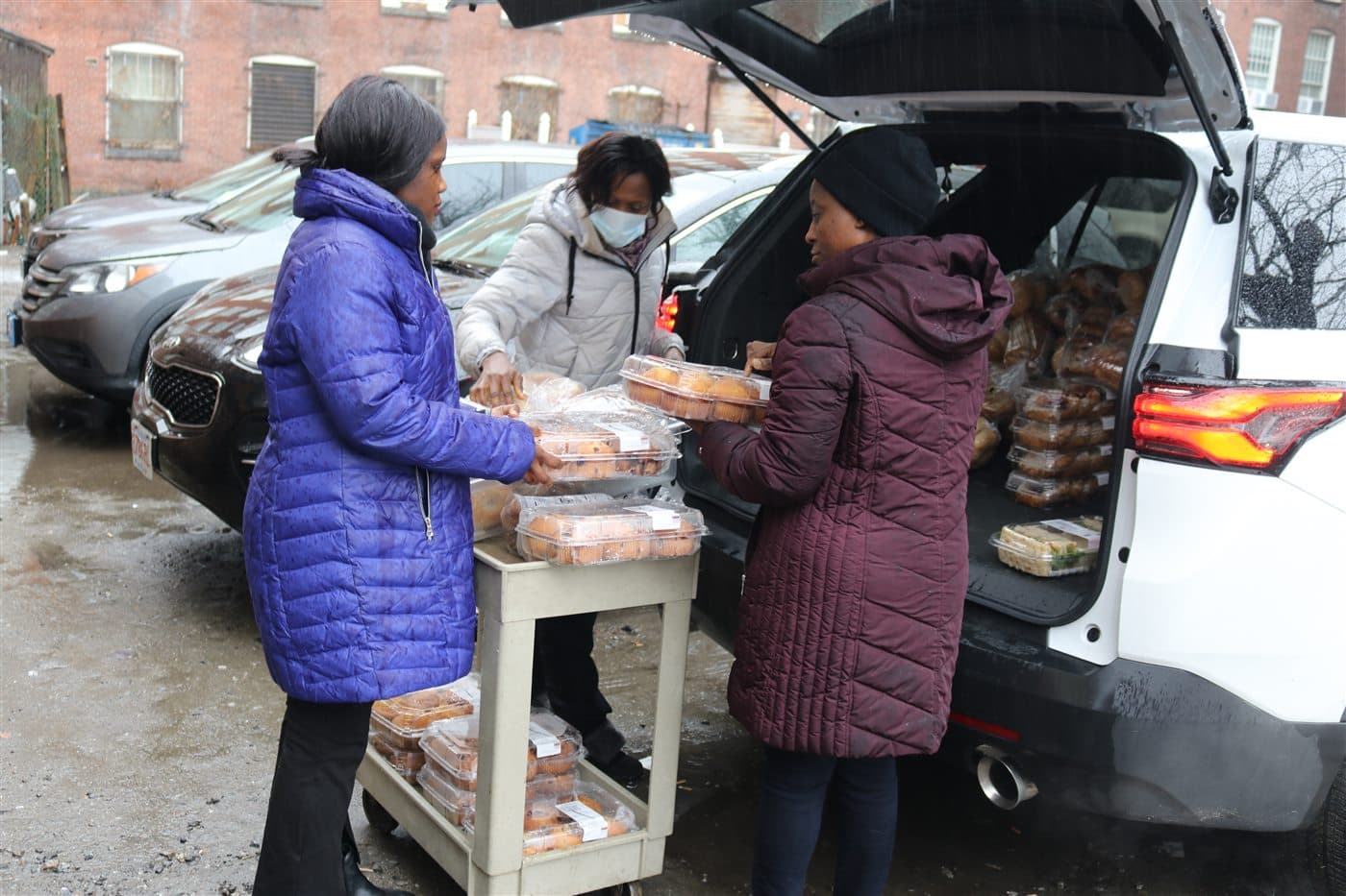 Volunteers loading prepared food at the back of an outreach vehicle