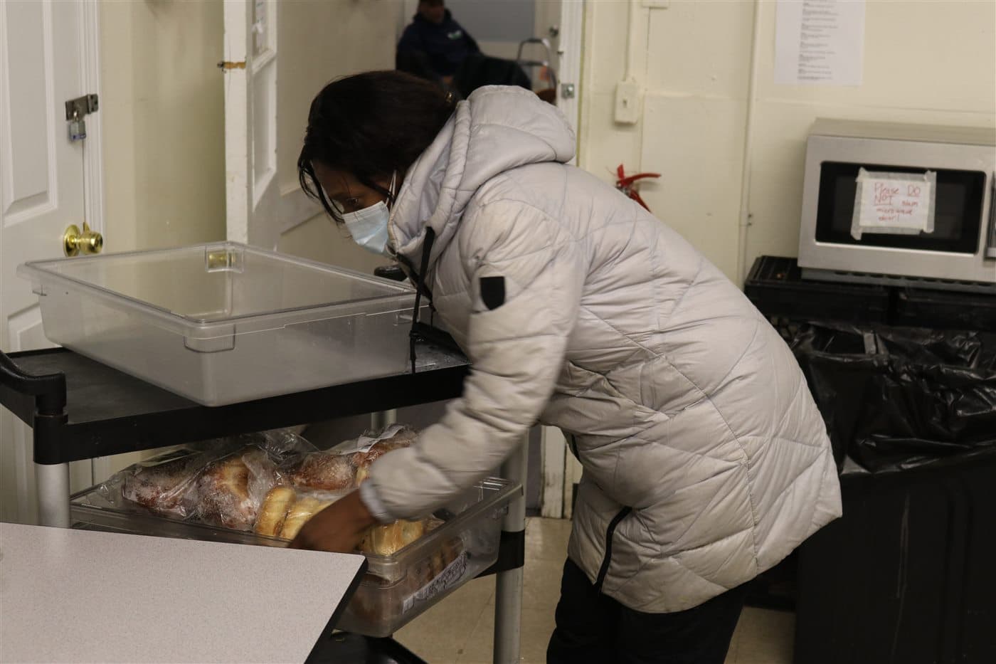 A volunteer packing bread into a large outreach container