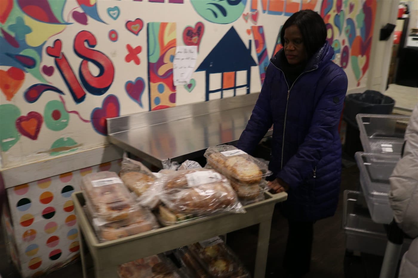 A volunteer pushing a cart filled with packaged bread