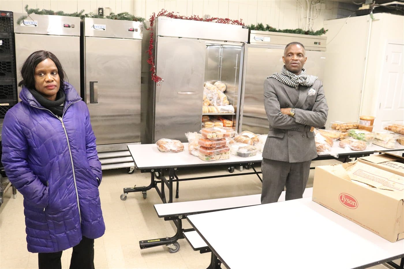 Two outreach leaders standing among prepared food and supplies