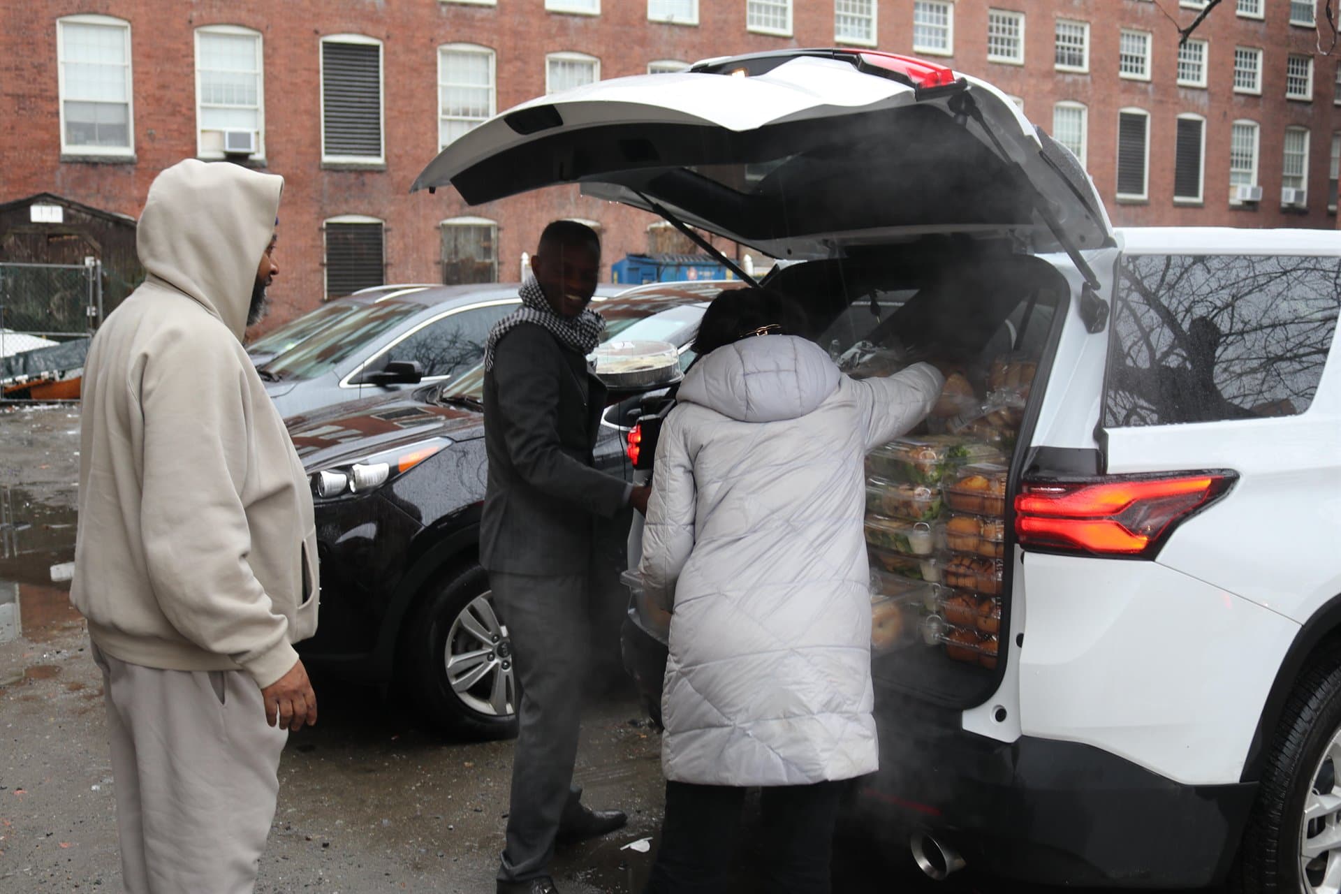 Pastor Henry Edward Ssuuna helping unload prepared food for community outreach in Boston