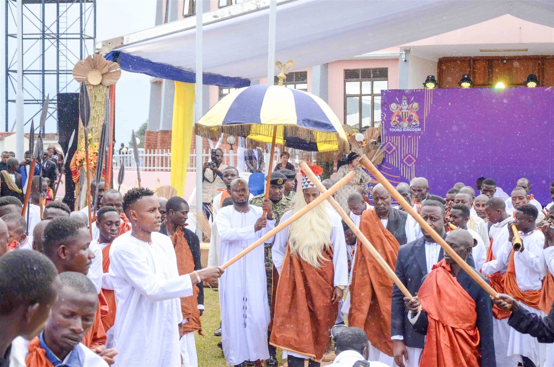 King Oyo performing Empango rituals under the royal umbrella, surrounded by clan elders in ceremonial dress